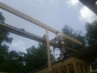 Carpenter setting a ridge beam over a new addition frame — Ice Dam Removal by Roofing Brothers in Sparrow Bush