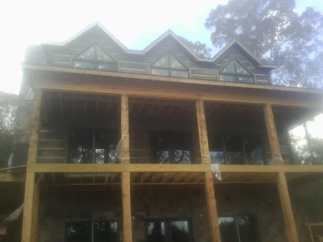Dormers and porch framing on a large log home under construction — Roof Coating work by our crew in Sparrow Bush