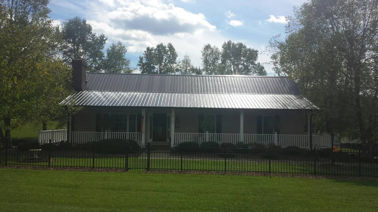 Gray metal roof on a brick ranch with a full width front porch — Gutter Guard Installation work by our crew in Sparrow Bush