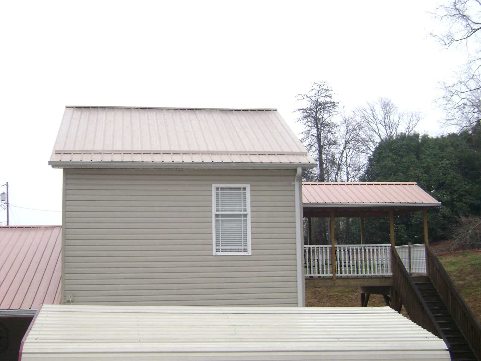 Tan metal roofs on a two story addition and attached porch, from a Roof Replacement job in Sparrow Bush