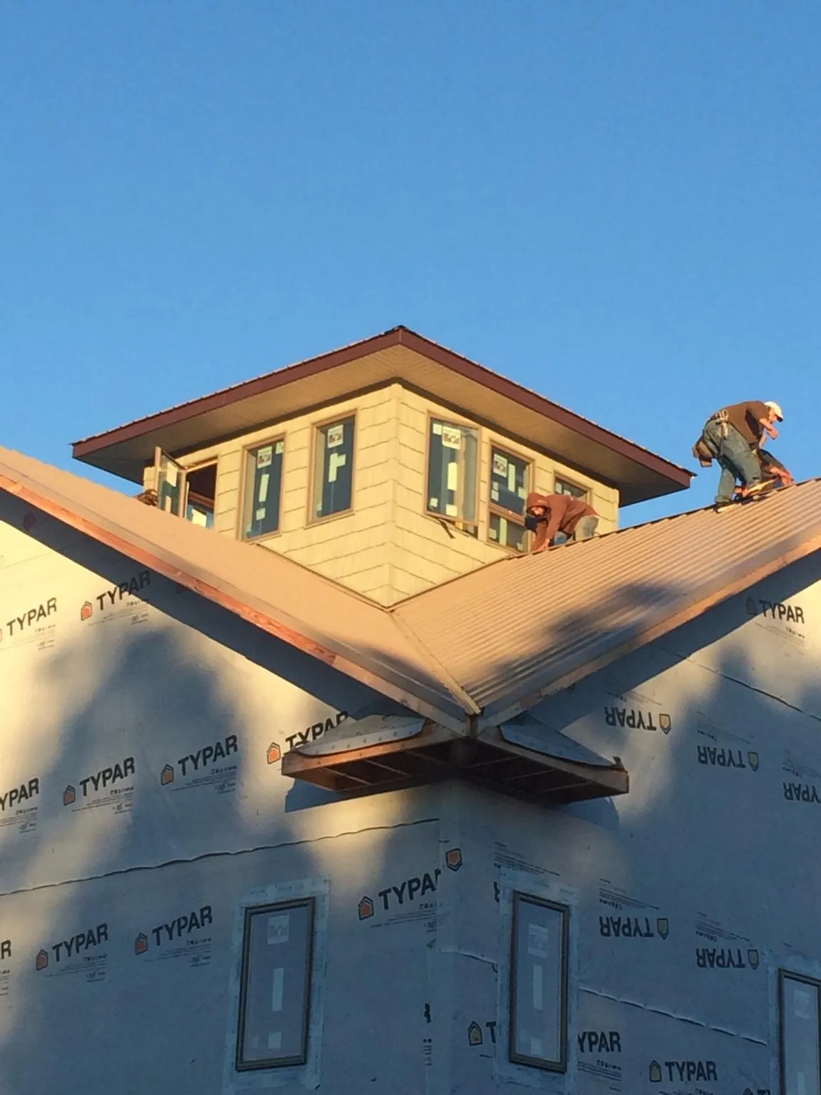 Roofers working around a rooftop cupola on a new metal roof at sunset — Roof Waterproofing in Sparrow Bush by Roofing Brothers